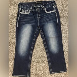 Dark wash blue jean capris with pocket embellishments